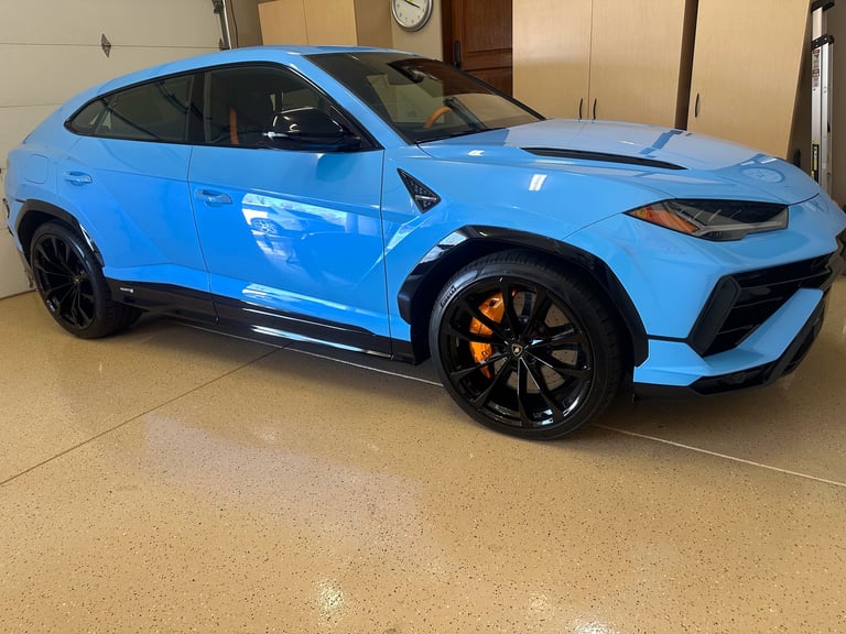 Bright blue sports SUV with black wheels and yellow brake calipers parked in a garage