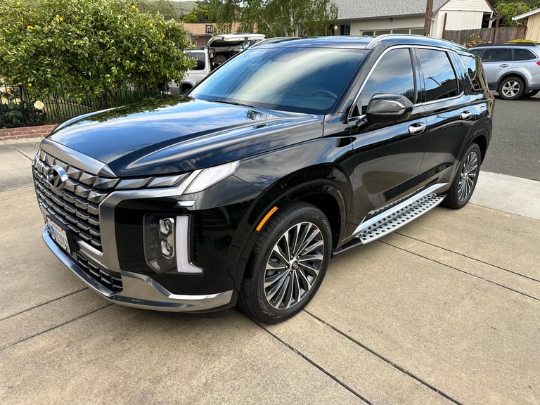 Black Hyundai Palisade SUV parked in driveway with chrome accents and alloy wheels