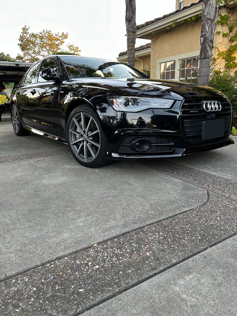 Black Audi luxury sedan parked in a driveway with modern house in background