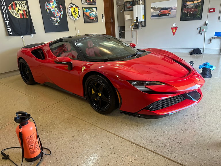 Red Ferrari sports car with open roof parked in garage workshop with posters and equipment