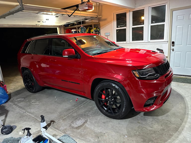 Red Jeep Grand Cherokee SRT parked in a garage with black wheels and red accents